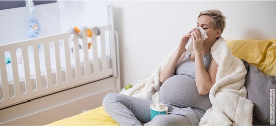 Eine schwangere Frau mit Schwangerschaftsschnupfen putzt sich die Nase.