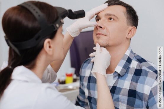 Ärztin untersucht einen Patienten, um die Ursache der trockenen Nase festzustellen